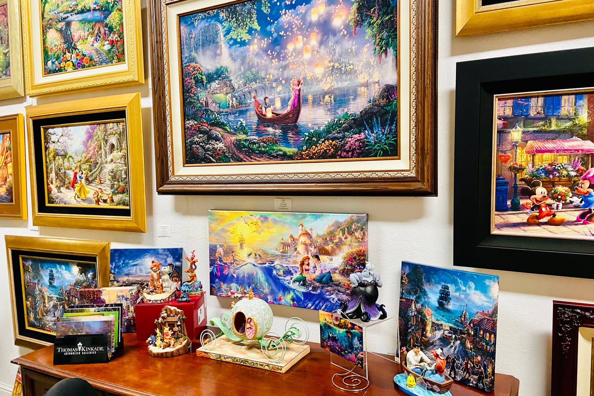 An array if different products offered like paintings and smaller art pieces on a wall and side table by ABS.