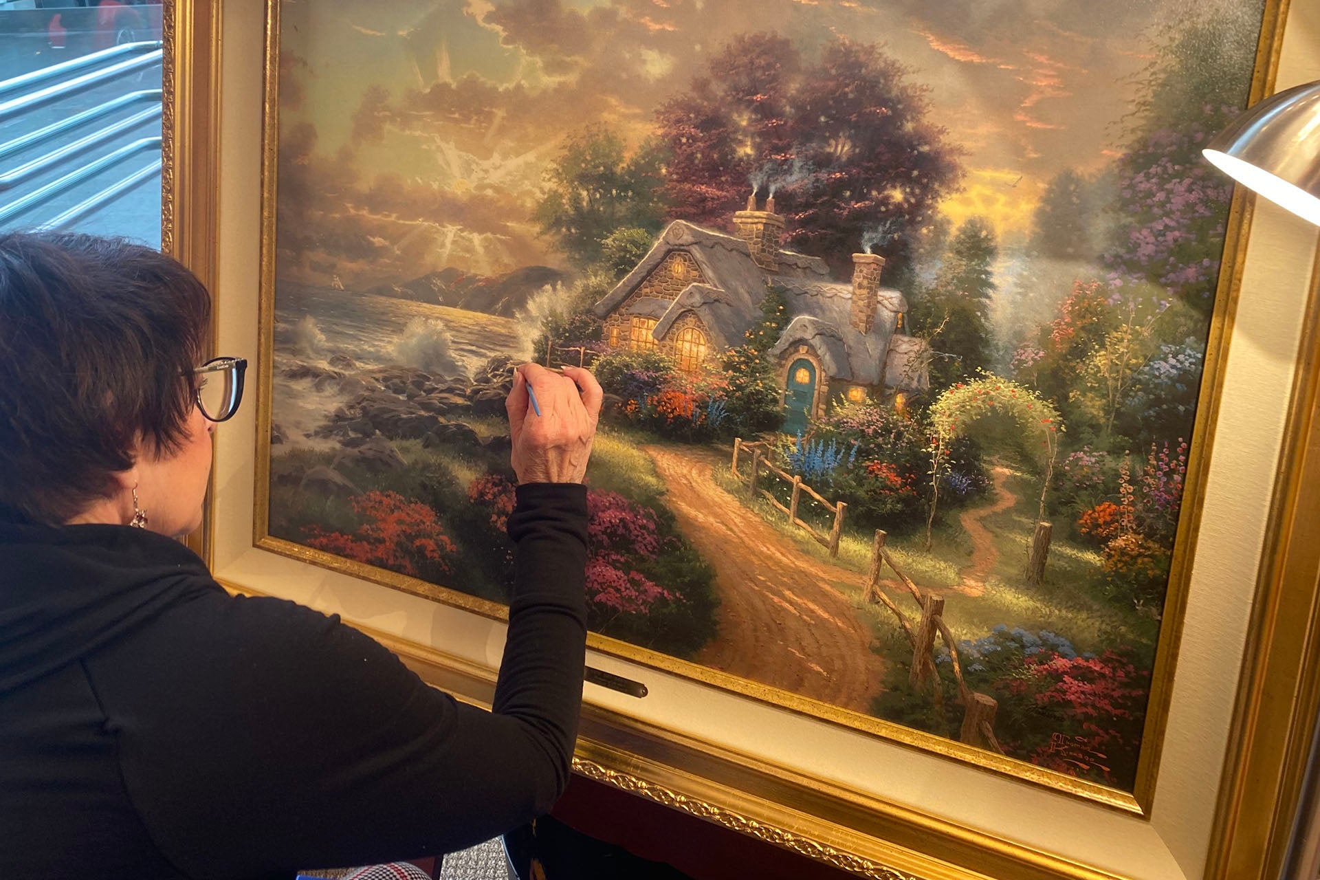 Artist hand-painting a Thomas Kinkade Studios canvas in the Art Brand Studios studio – Meet the Artists of Art Brand Studios
