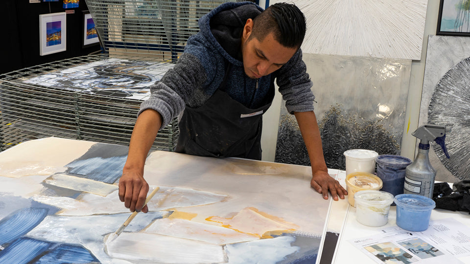 Artist hand-texturing and detailing canvas artwork in Art Brand Studios workshop – Wholesale art production process